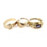 Three 9ct gold rings. Comprising a signet ring, a buckle ring and a ring set with a red stone,