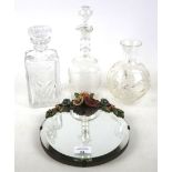 A small wall mirror, glass vase and two decanters.