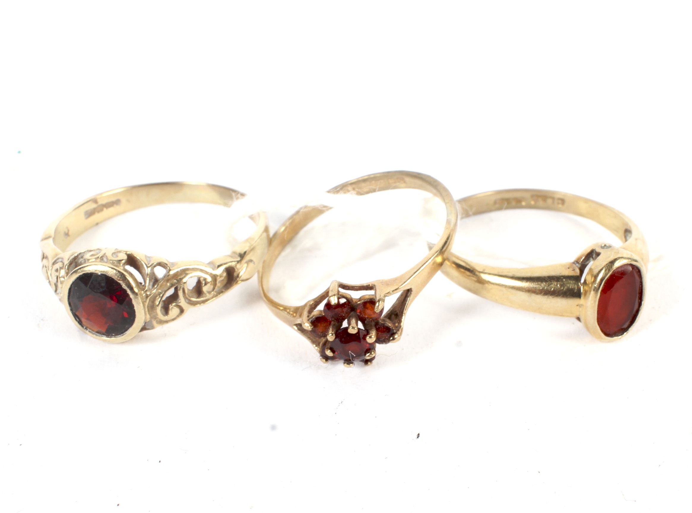 Three 9ct gold rings. Each set with red stones, including a cluster example,