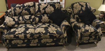A contemporary sofa with matching armchair decorated with foliate decoration with outswept arms