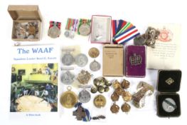 A collection of assorted medals, cap badges and military buttons.