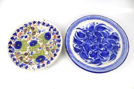 Two Delft plates. One with a colourful floral design, diam 31.