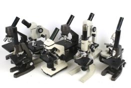 Nine assorted student microscopes.