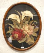 An oval veneer framed woolwork and embroidery picture of flowers.