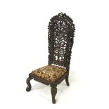 An Indian chair. Carved and pierced back with floral upholstery, raised on carved legs, H121cm.