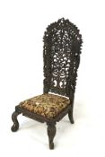 An Indian chair. Carved and pierced back with floral upholstery, raised on carved legs, H121cm.