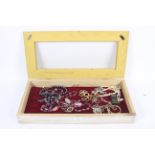 A quantity of costume jewellery in shades of mauve in a display box