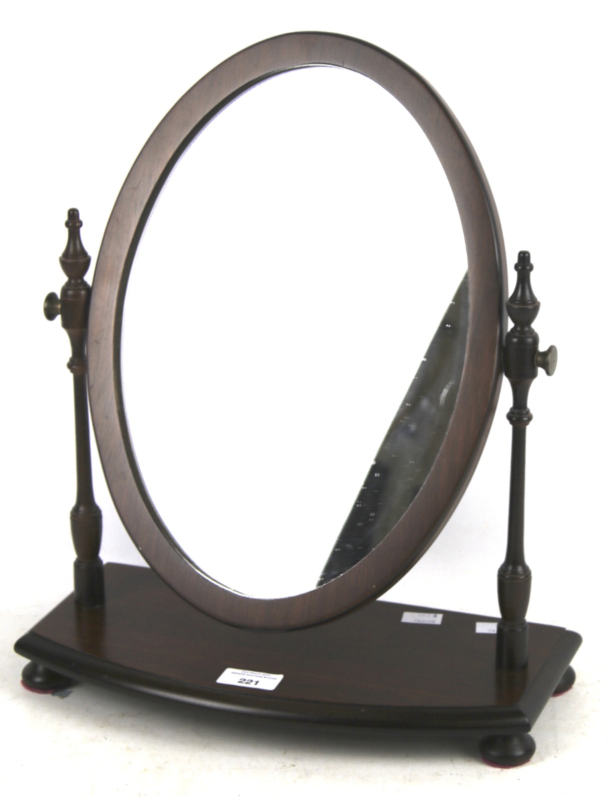A contemporary dressing table mirror. Of oval form on wooden turned supports and ball feet, H45cm.