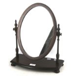 A contemporary dressing table mirror. Of oval form on wooden turned supports and ball feet, H45cm.