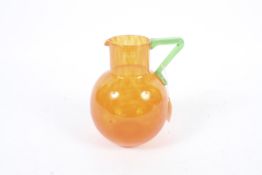 An orange glass jug of bulbous form with an angular green glass handle.