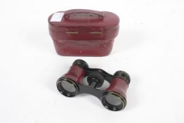 A vintage pair of red leather covered opera glasses in a case, stamped Chevalier Paris.
