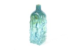 A large Mdina turquoise glass bottle vase with textured bark ground.
