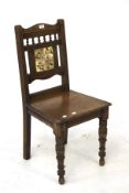 An oak hall chair. Back inlaid with a tile on turned legs, H91cm x D41cm x W44cm.