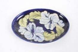 A 1980s Moorcroft oval lilly pattern dish. With pale blue and green lillies on a blue ground.