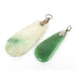 Two jade pendants. One green and the other white and carved with a flash of green.