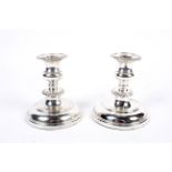 A pair of plated short round candlesticks with gadrooned nozzles and knopped stems on domed bases