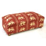 An upholstered Ottoman. red with white lion pattern on wooden feet, H43cm x D57cm W124cm.