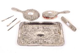 A silverplated tray with embossed decoration and a silver back dressing table set.