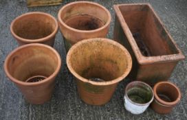 Six terracotta plant pots and a trough.