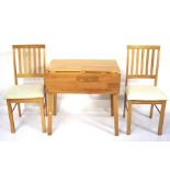 A contemporary wooden drop leaf kitchen table and a pair of chairs.
