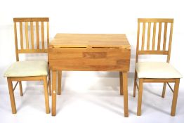 A contemporary wooden drop leaf kitchen table and a pair of chairs.