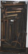 A collection of assorted vintage blacksmith's tool on a display board.