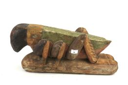 A large Indonesian carved and stained wooden figure of a grasshopper or cricket.
