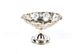 A silver pedestal bon bon dish with pierced fretwork panels below a pie crust border.