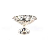 A silver pedestal bon bon dish with pierced fretwork panels below a pie crust border.