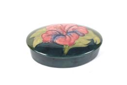 A Moorcroft green ground oval trinket box and cover in the hibiscus pattern.