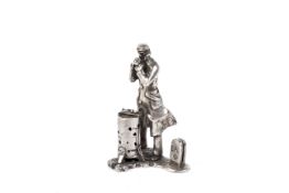 A silver place name stand in the form of a Victorian workman keeping warm.