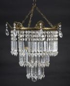 An early 20th century gilt-metal and brass three-tier chandelier with cut-glass lustre pendant