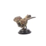 An early 20th century cold painted metal model of a bird on wooden base.