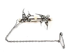 A late Victorian pearl and diamond brooch in the form of a pair of swallows on a knife-edge bar.