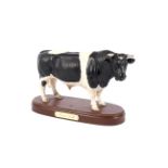 A Royal Doulton model of a Fresian Bull on an inscribed wooden base. Printed black marks, 29.