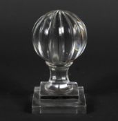A large glass paperweight in the form of a notch-cut sphere on faceted socle and stepped base. 16.