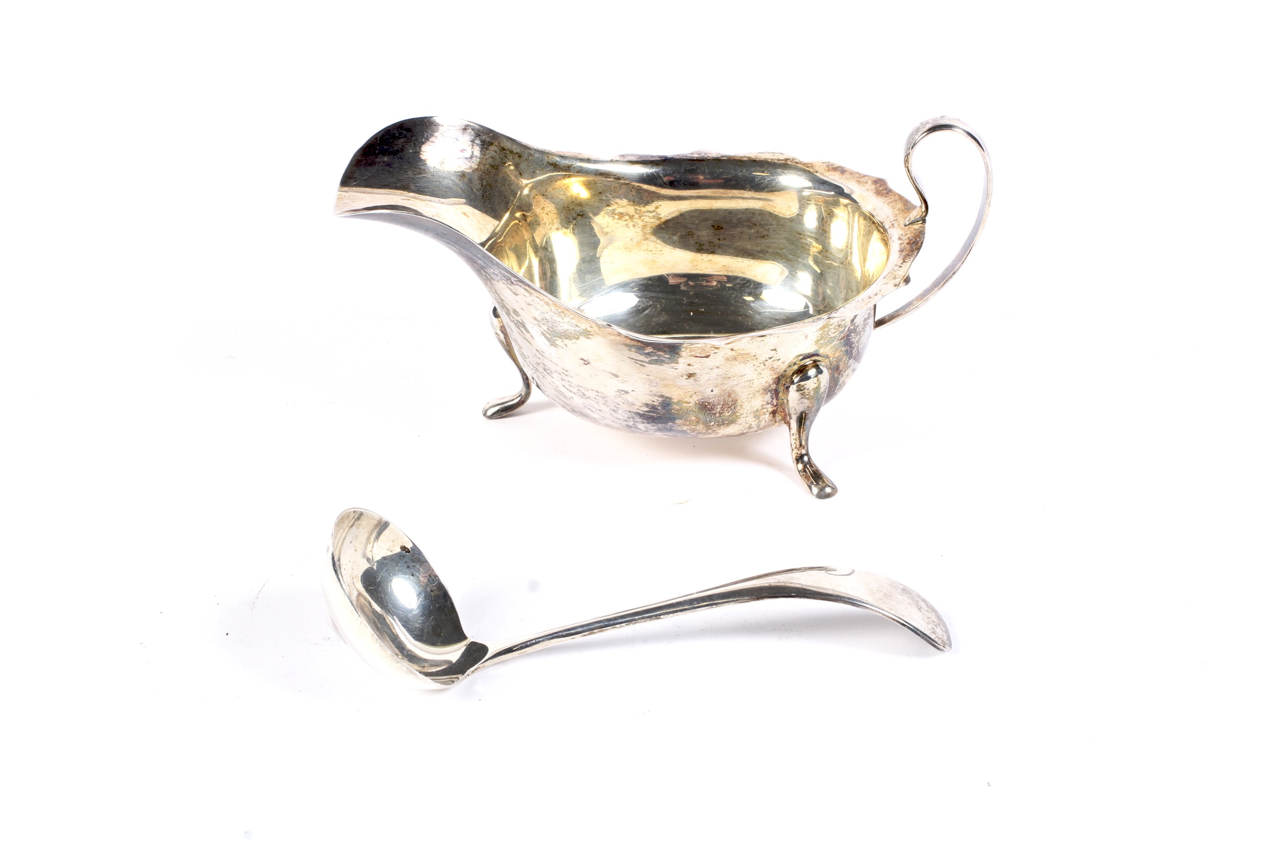 A silver sauce boat and a sauce ladle.