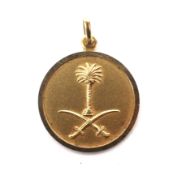 A round disc pendant chased with the emblem of Saudi Arabia. Stamped '750', 24mm diameter, 5.