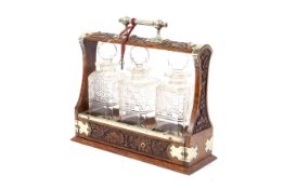 An Edwardian three-decanter brass-mounted oak tantalus.