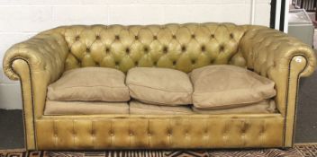 A tan leather Chesterfield sofa bed.