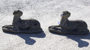 A pair of stone greyhounds lying down.