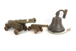 Two contemporary brass and wooden models of ship canons and a ships bell.