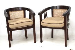 A pair of tub style mahogany framed open armchairs. With cane seats and backs.