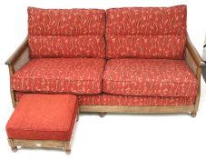 An Ercol wooden framed three seat bergere sofa and a matching footstool.