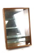 A wall mounted display cabinet with glazed door. With mirrored back and four glass shelves.