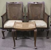 Two Edwardian Bergere armchairs and a similar footstool.