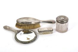 A silver backed hairbrush, mirror and two pots.
