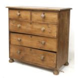 A 20th century pine chest of drawers. Two short over three long drawers, on bun feet.