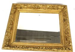 A bevelled edge wall mirror with gilt pitch pine frame. Heavily decorated with acanthus leaves.