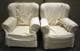 A pair of vintage wingback armchairs with cream fitted covers.